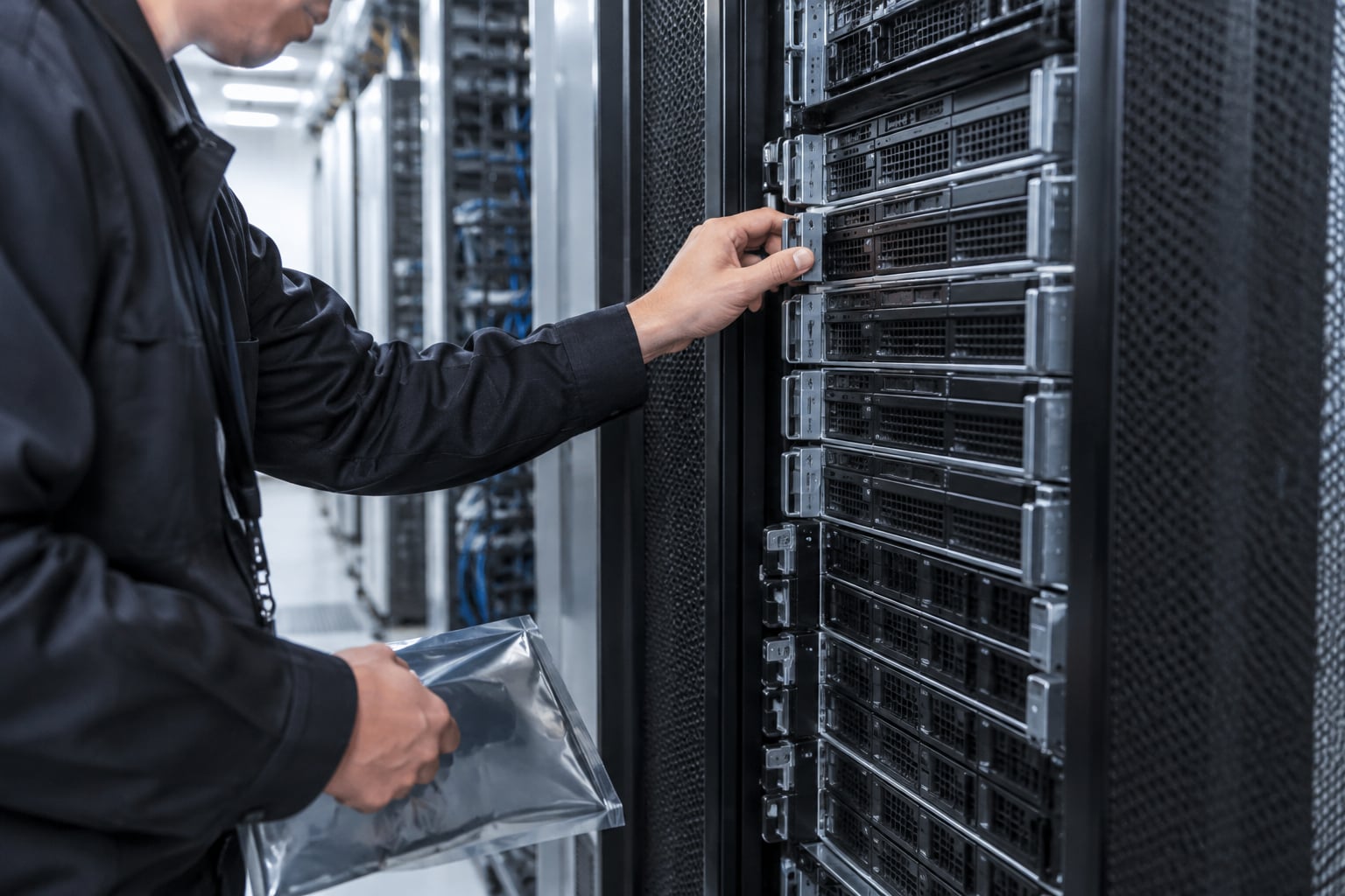 Mão de engenheiro encaixa lâmina de servidor em chassi de datacenter bem iluminado.